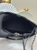 Black handbag open view with gold zipper pull and chain strap