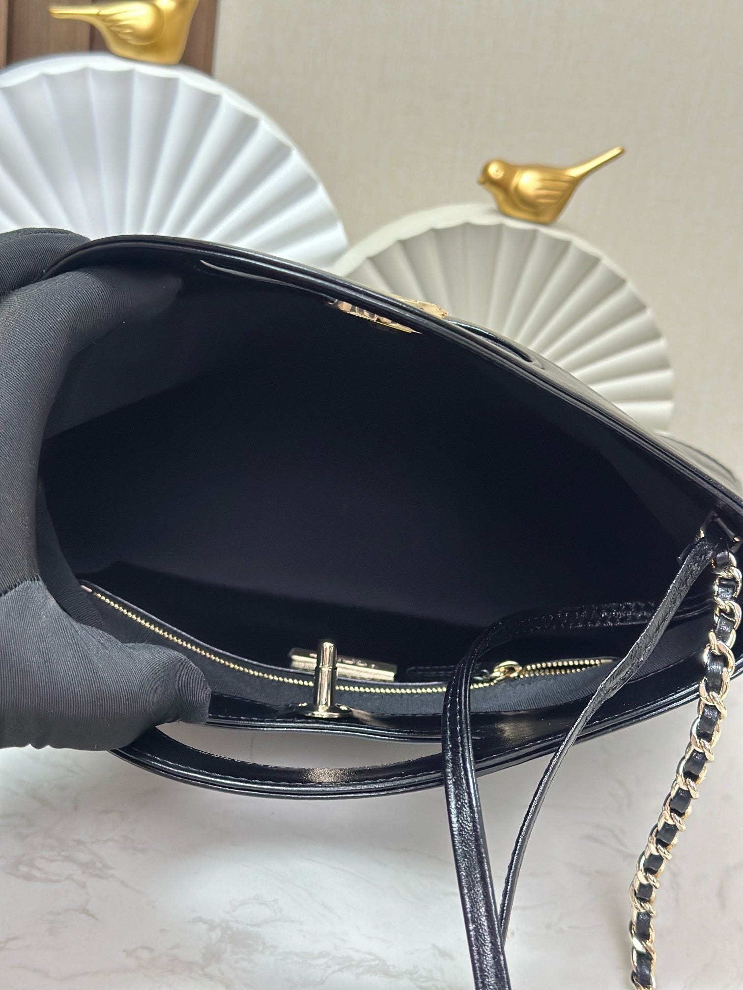 Black handbag open view with gold zipper pull and chain strap