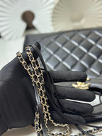 Black quilted handbag detail with layered gold-tone chain strap