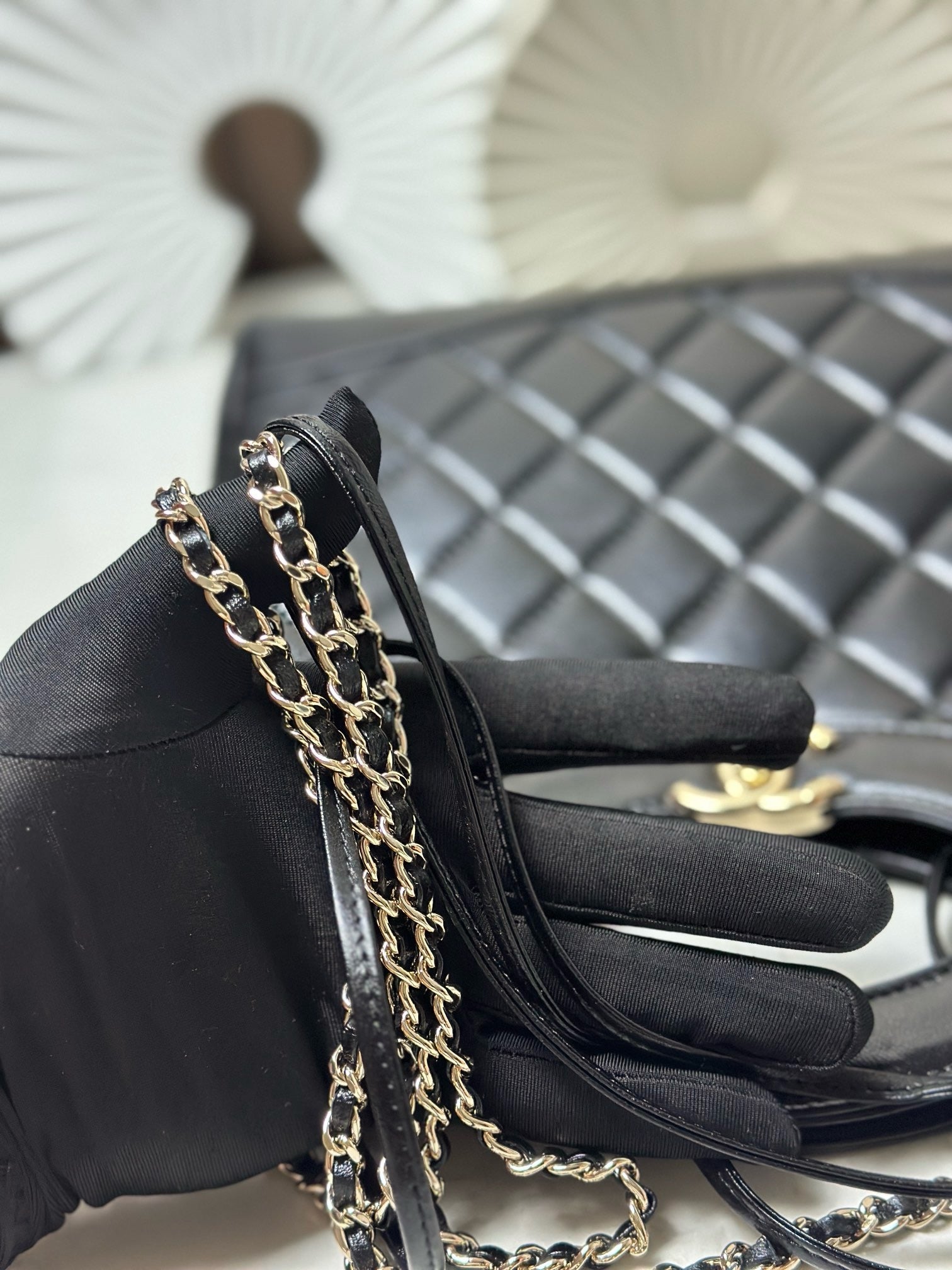 Black quilted handbag detail with layered gold-tone chain strap