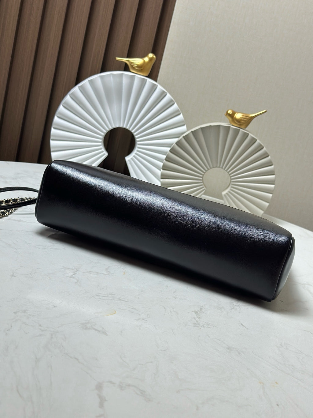 Black quilted clutch with gold chain strap, laid flat on a tabletop