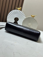 Black quilted clutch with gold chain strap, laid flat on a tabletop