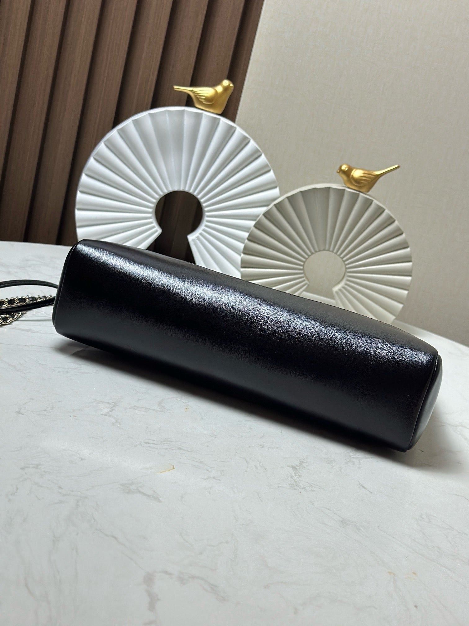 Black quilted clutch with gold chain strap, laid flat on a tabletop