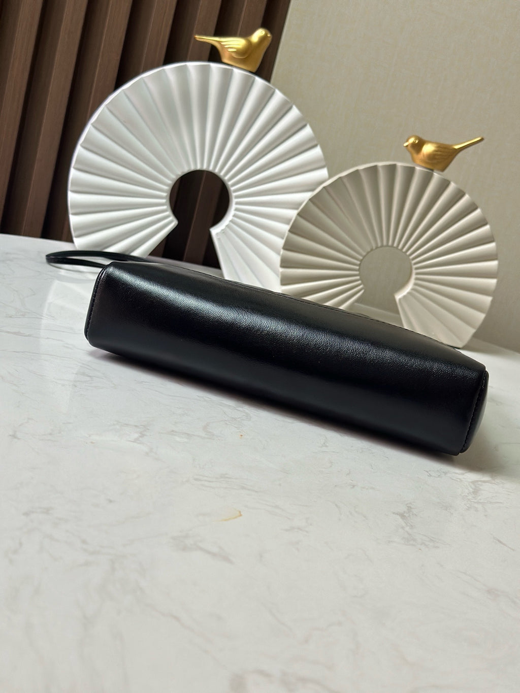 Black leather clutch-style bag with gold-tone clasp hardware and chain strap