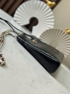 Black quilted Chanel handbag with chain strap, angled view of front pocket and top