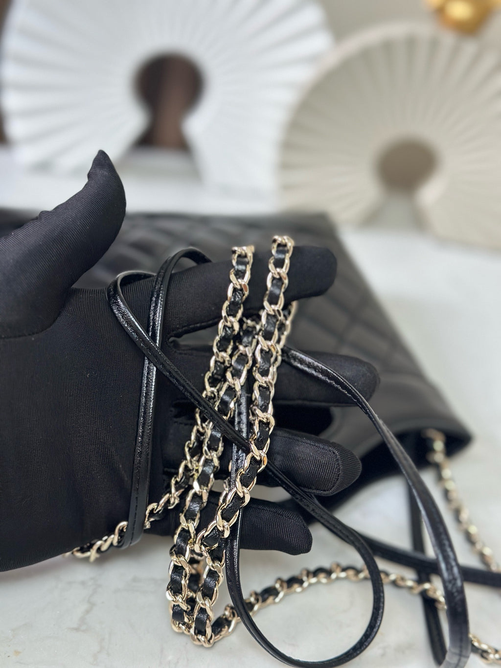 Small black quilted handbag with double chain strap and loop top handle, angled view