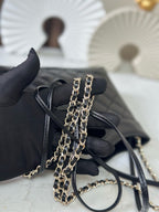 Small black quilted handbag with double chain strap and loop top handle, angled view