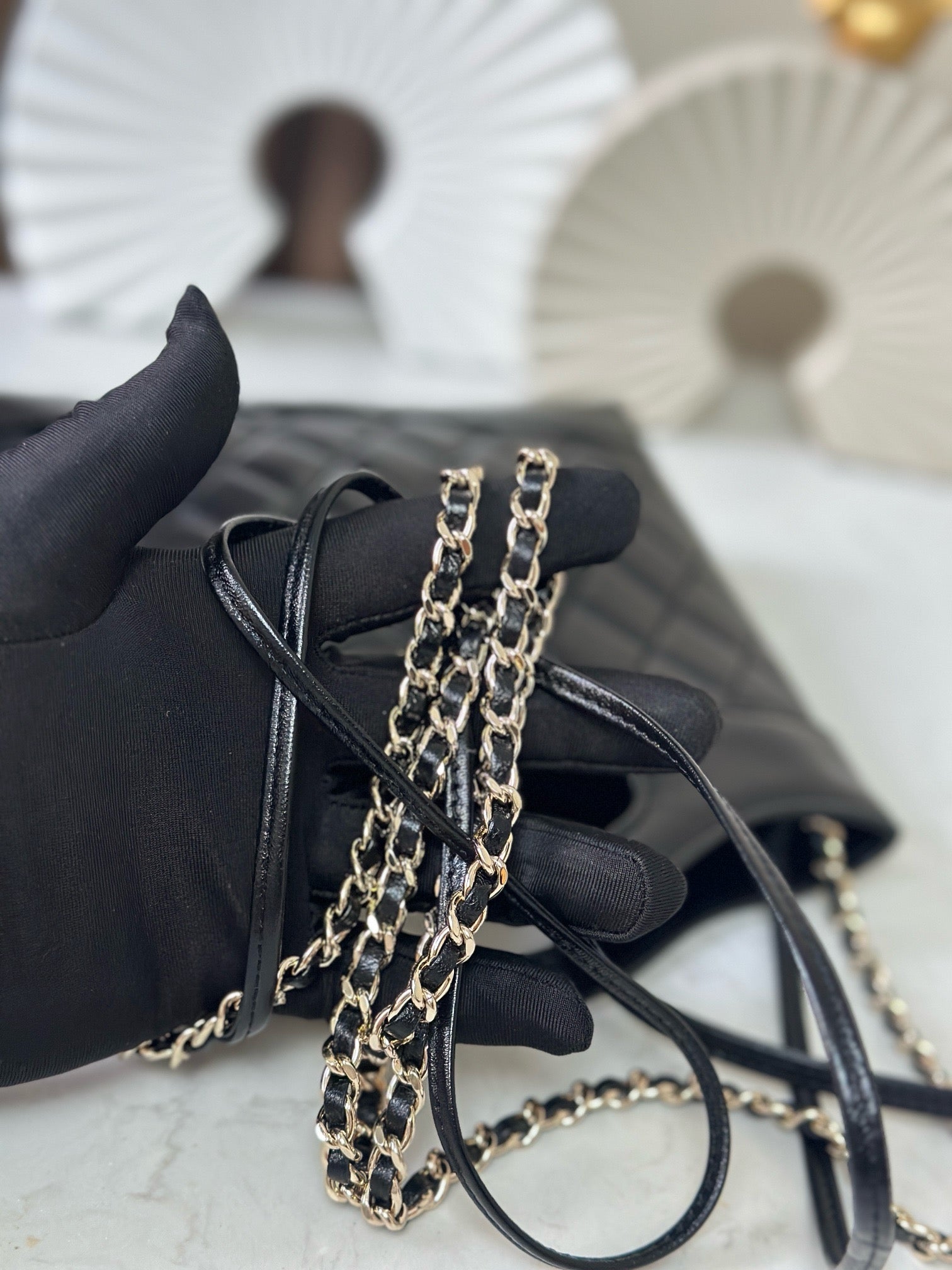 Small black quilted handbag with double chain strap and loop top handle, angled view