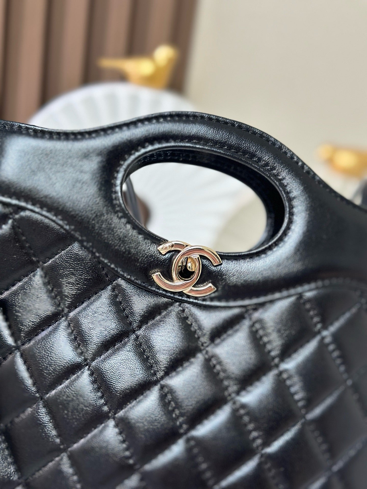 Close-up of black quilted handbag with oval logo ring and gold-tone Chanel hardware