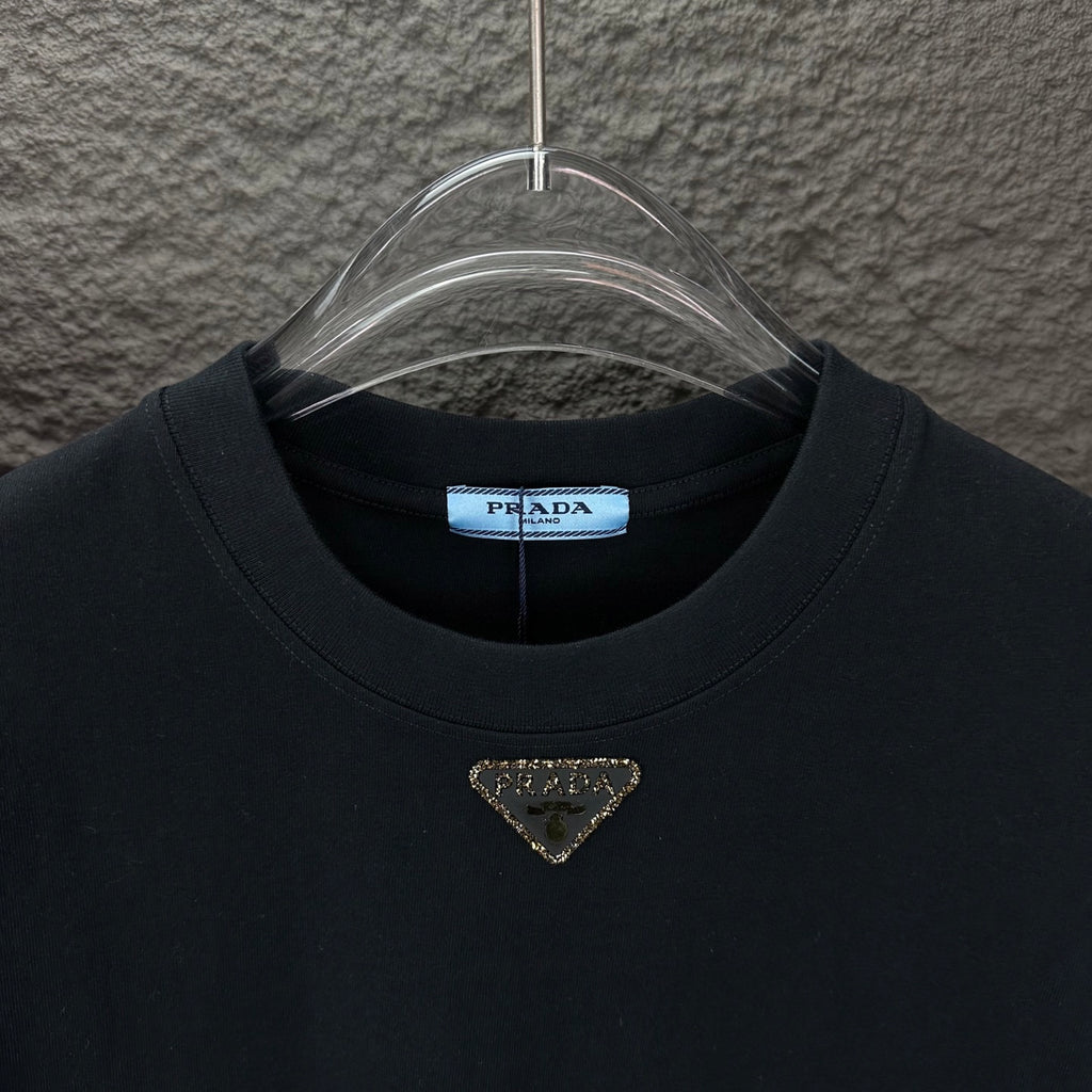 Prada black crewneck T-shirt with gold triangle logo, front neckline close-up