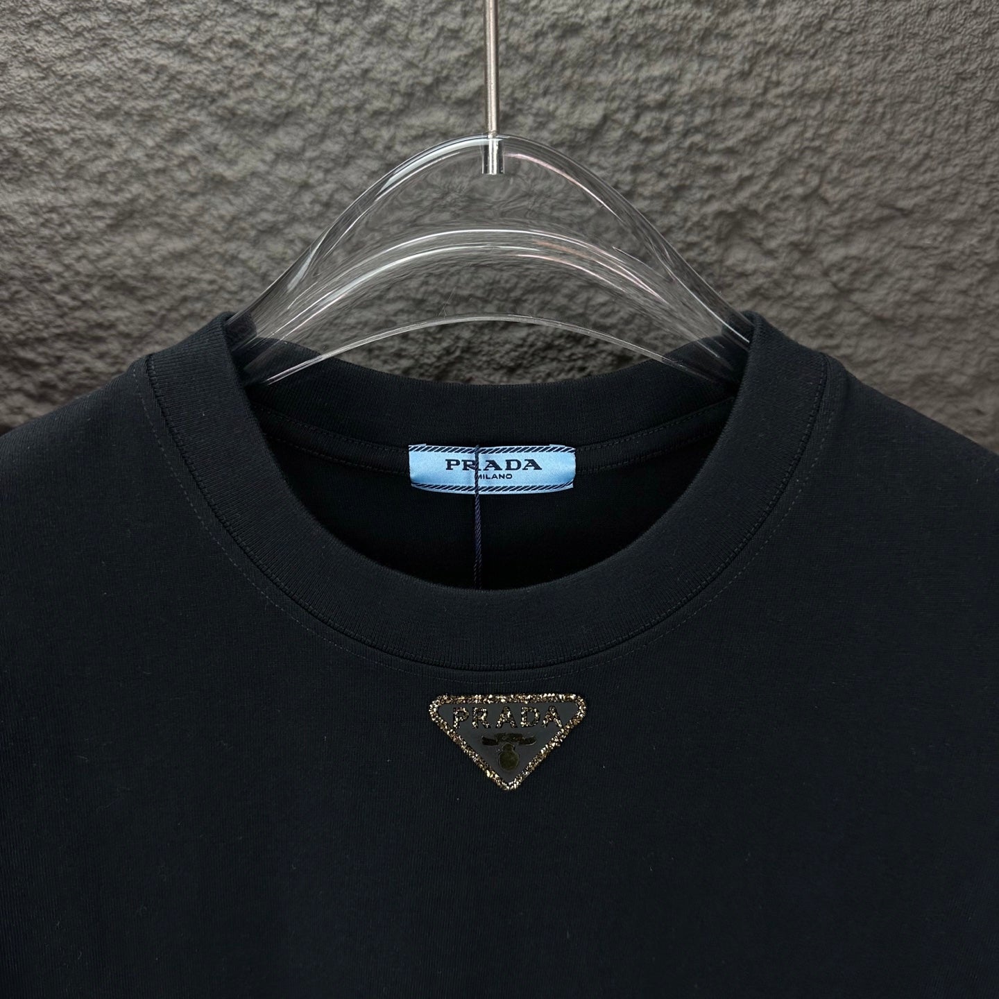 Prada black crewneck T-shirt with gold triangle logo, front neckline close-up