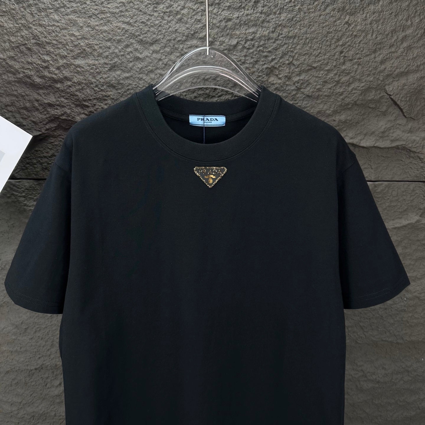 Prada black short-sleeve T-shirt with small gold triangle logo, front view