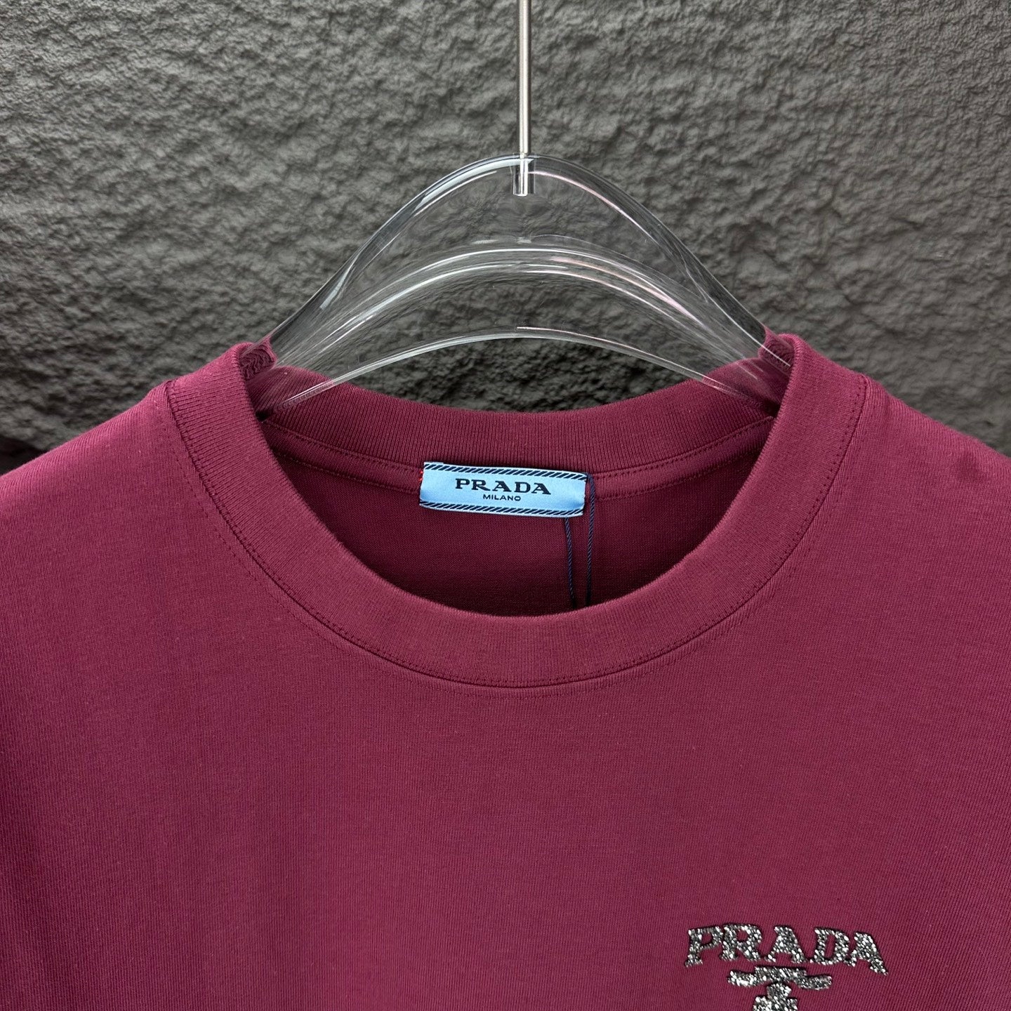 Prada short-sleeve T-shirt neckline with PRADA logo on dark berry fabric.
