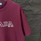 Burgundy crewneck Prada T-shirt sleeve detail with PRADA MIL ANO logo