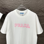 White short-sleeve T-shirt with pink PRADA MIL ANO logo on the chest.