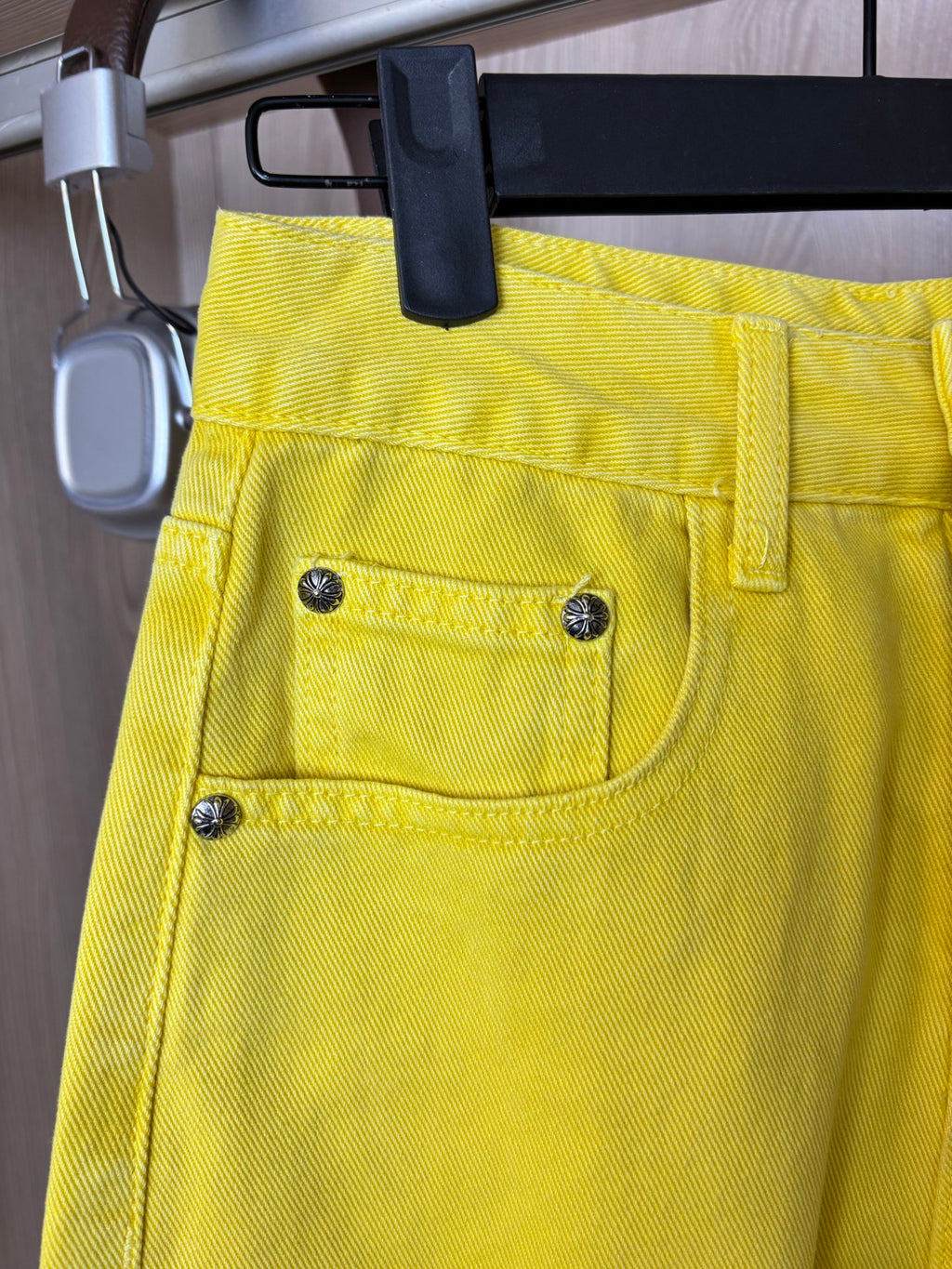 Yellow pants close-up of waistband, front pockets, and metal button accents.