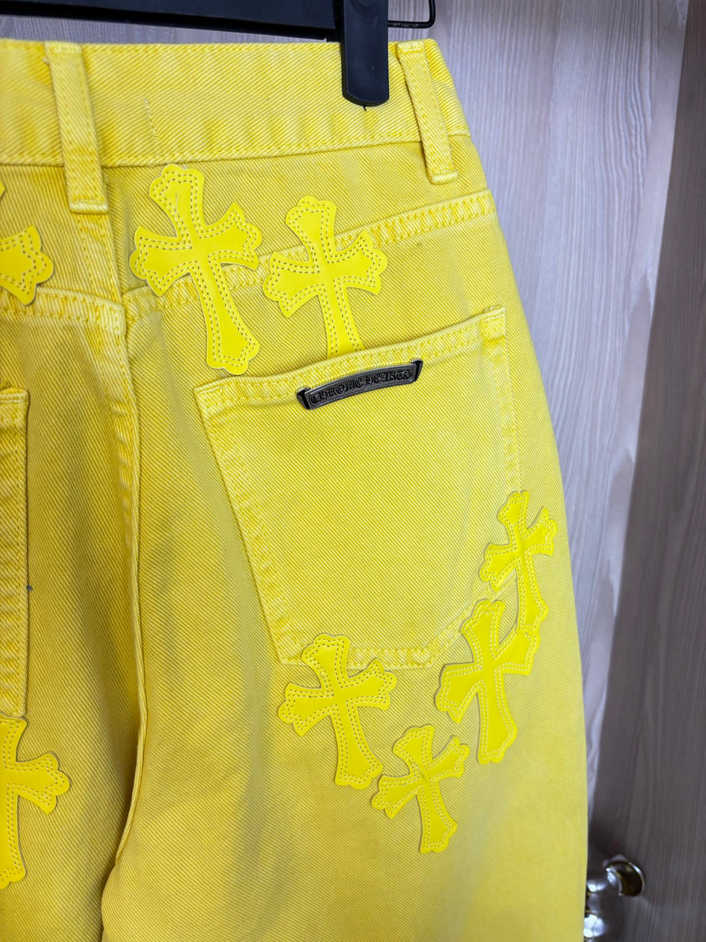 Yellow pants back view with belt loops, back yoke label, and cross appliqué details.