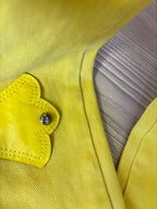 Yellow pants close-up of a button and stitched patch pocket panel.