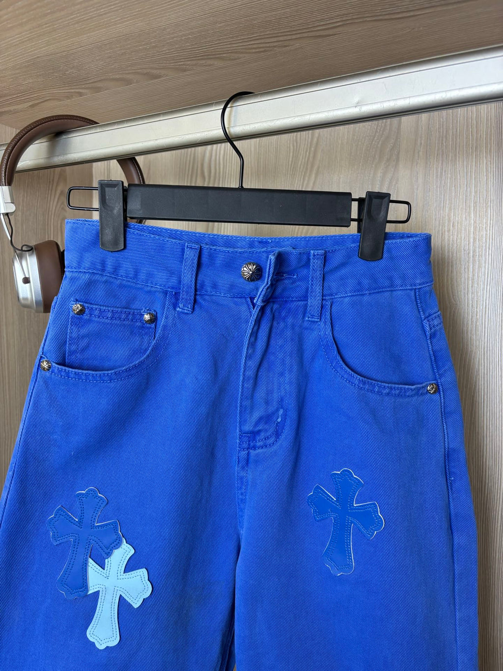 Blue denim pants on hanger with front button and slanted pockets
