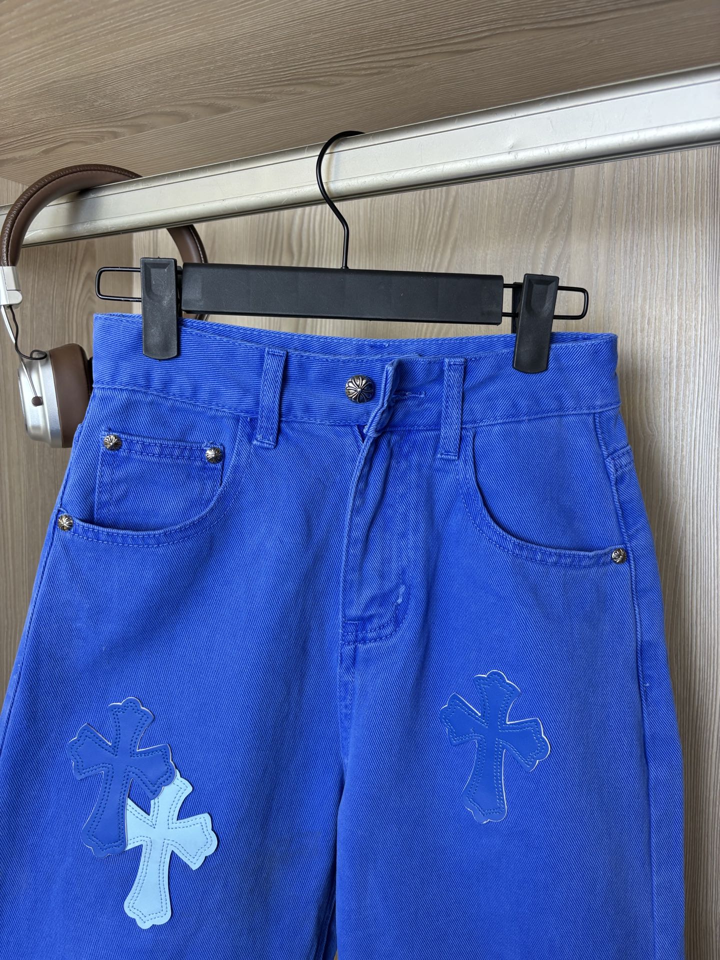Blue denim pants on hanger with front button and slanted pockets