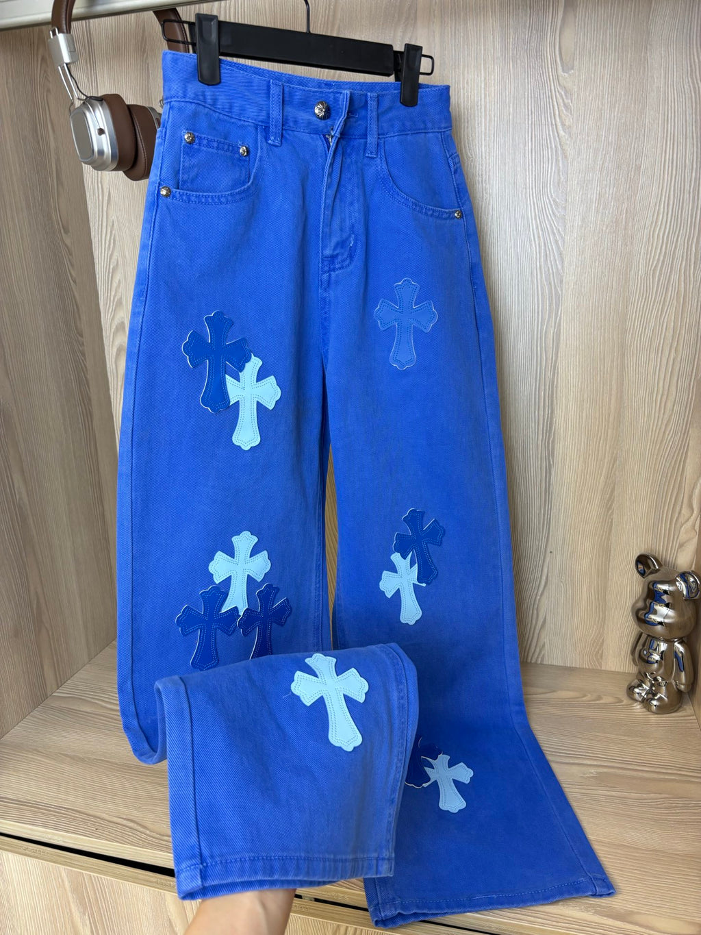 Blue denim pants with white appliqué cross shapes and button fly