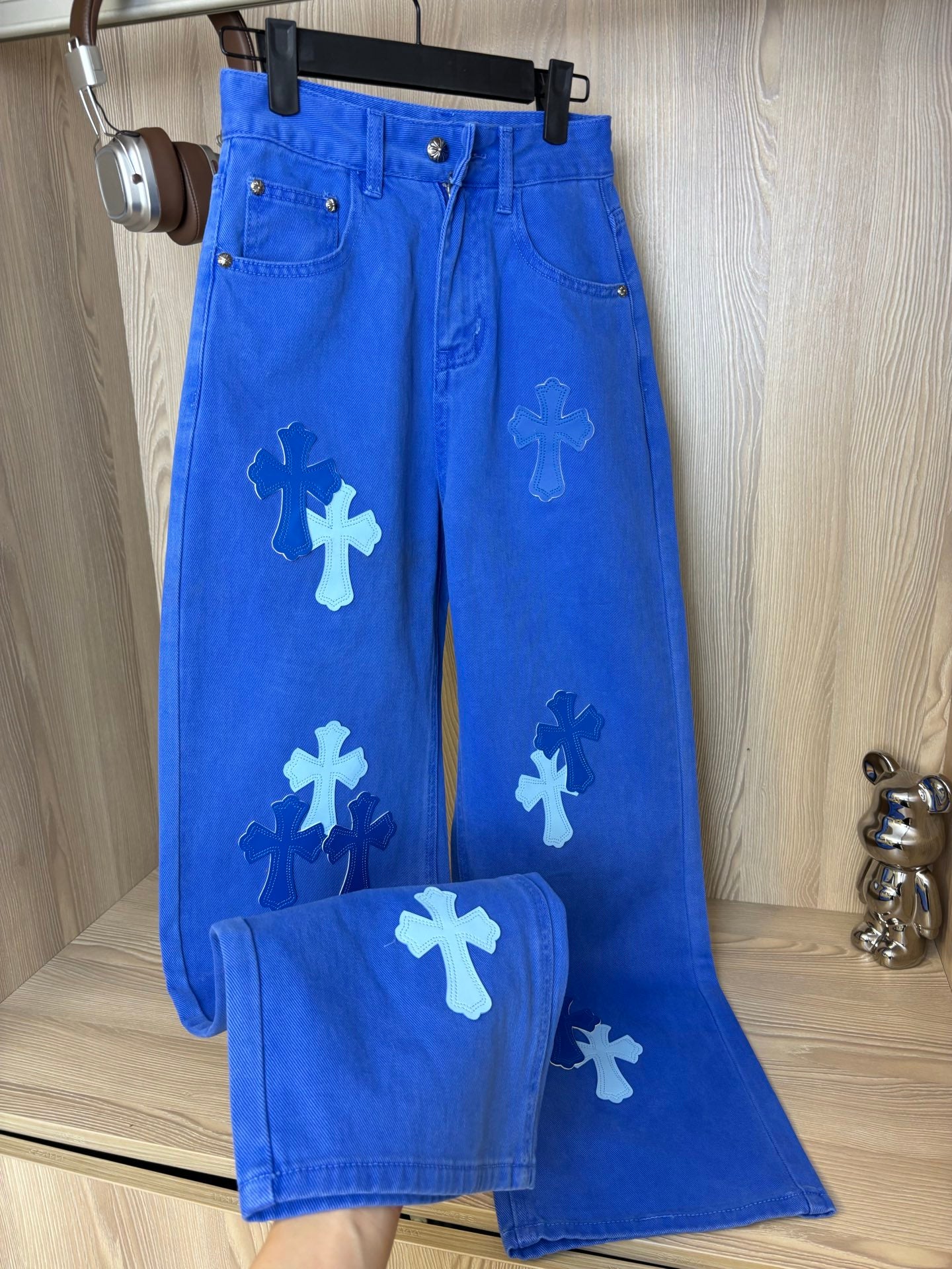 Blue denim pants with white appliqué cross shapes and button fly