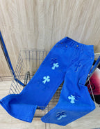 Blue denim pants with white cross patches, back view, button closure