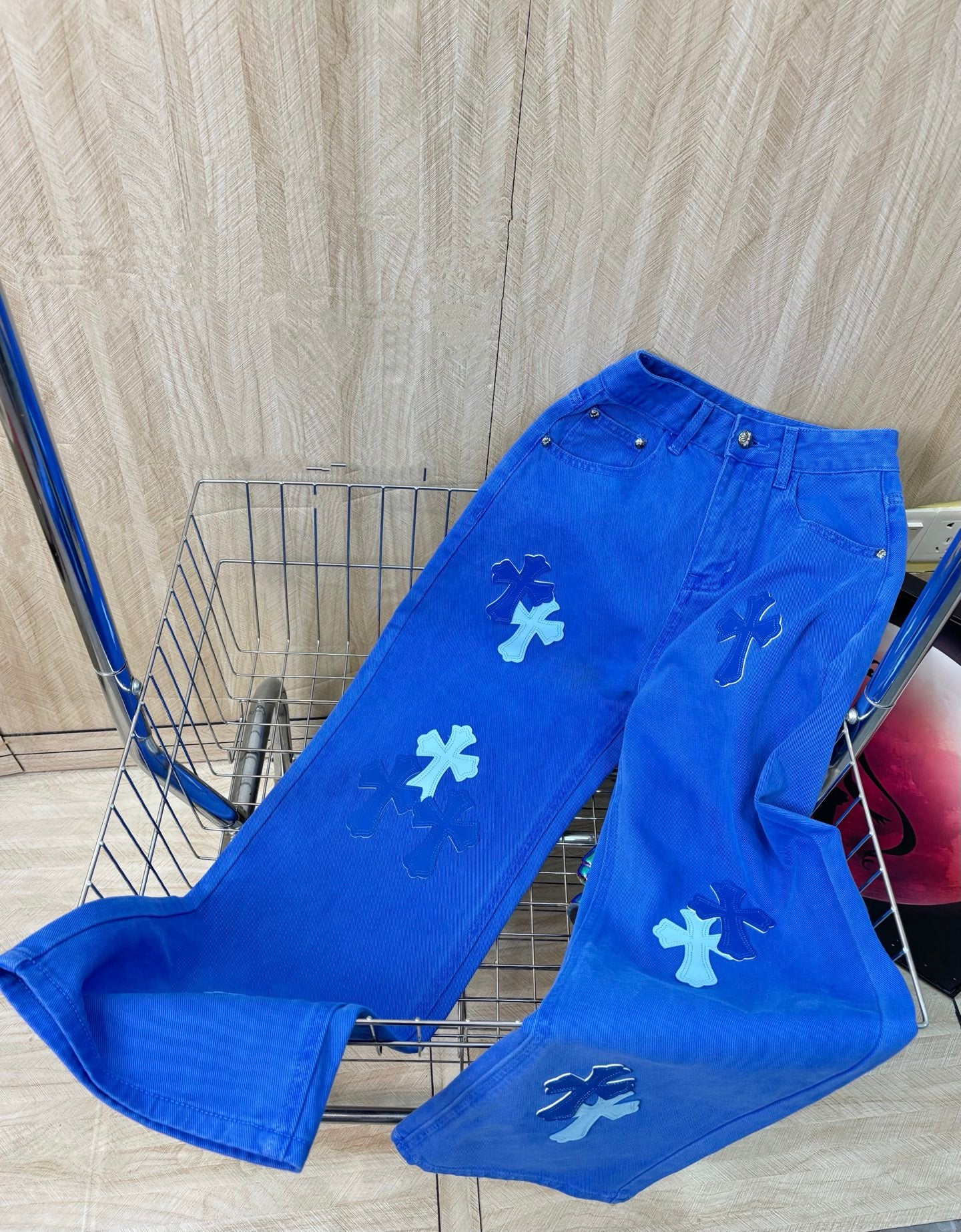 Blue denim pants with white cross patches, back view, button closure
