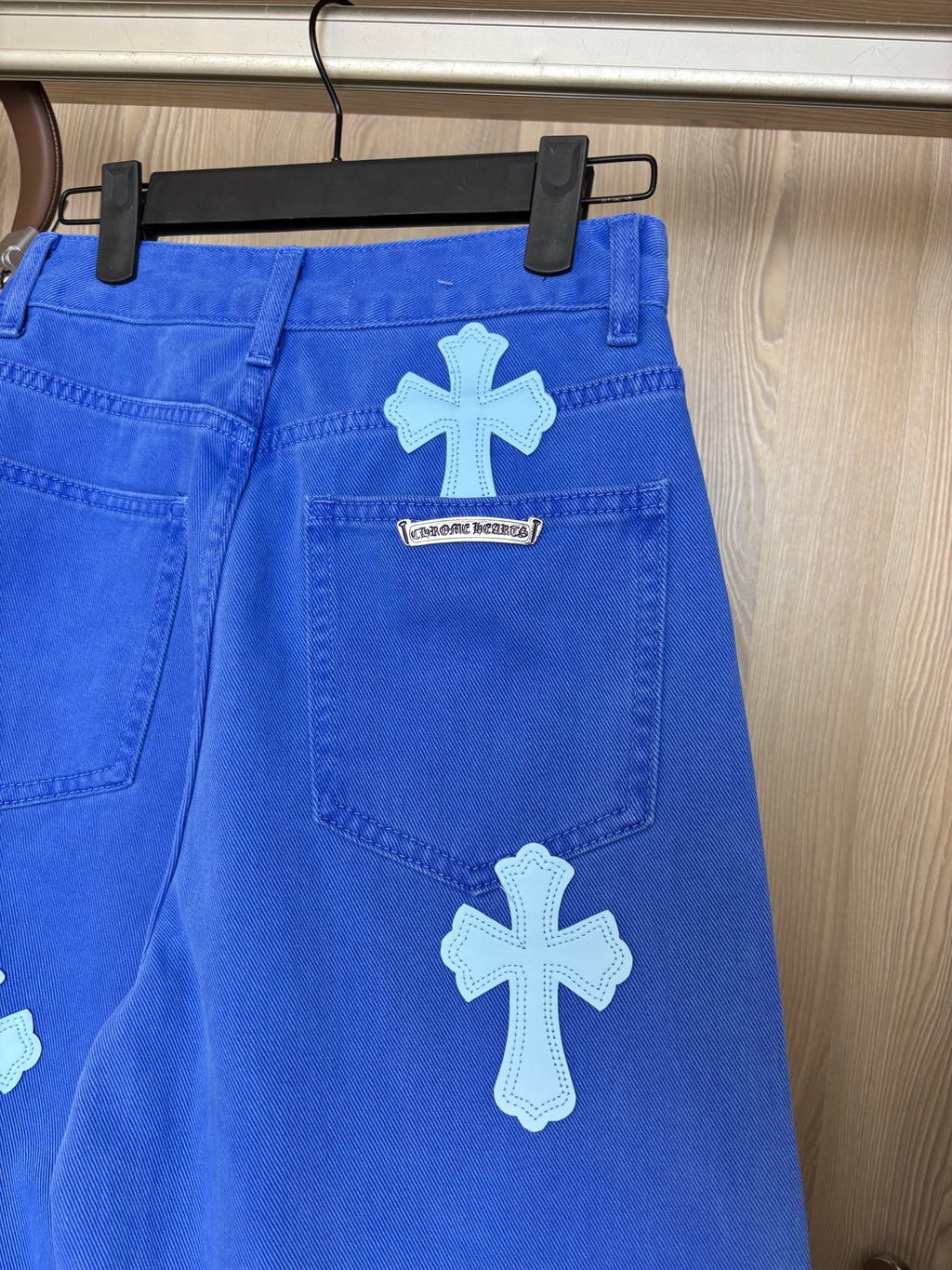 Blue denim pants with white cross patch on thigh and small center label