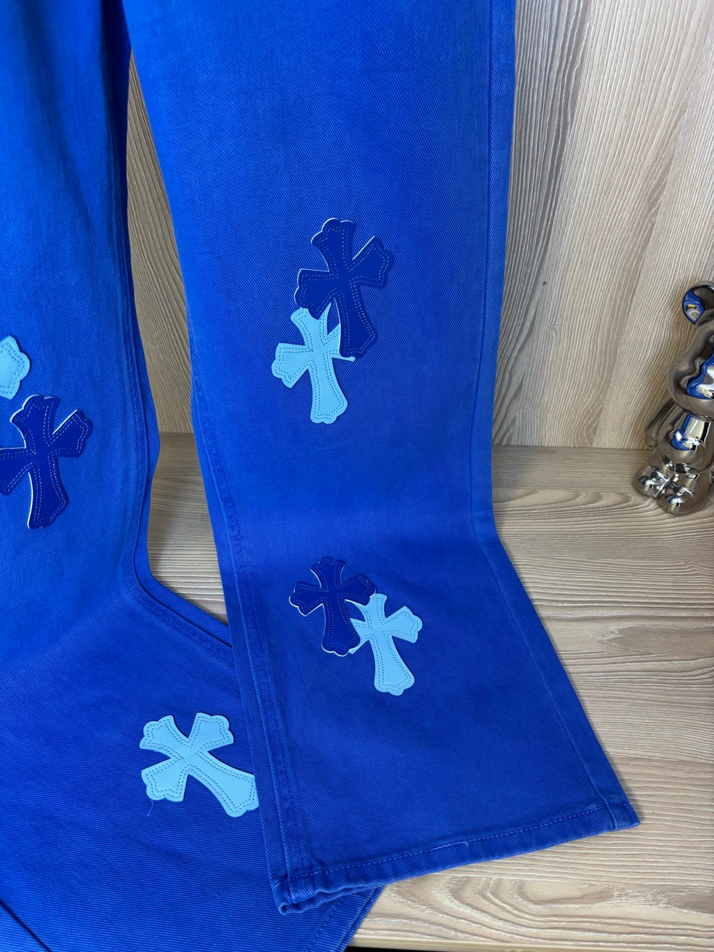 Blue denim pants with white cross appliqué on legs and tapered hem