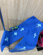 Blue denim pants with scattered white cross patches and waistband details