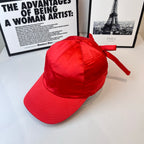Red cap with bow tie on crown and curved brim.