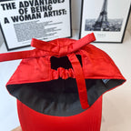 Red cap with black interior lining and bow-tied top strap.