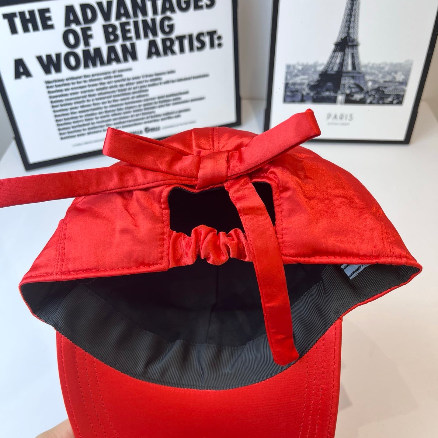 Red cap with black interior lining and bow-tied top strap.