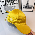 Prada yellow satin cap with triangular Prada logo patch on the front