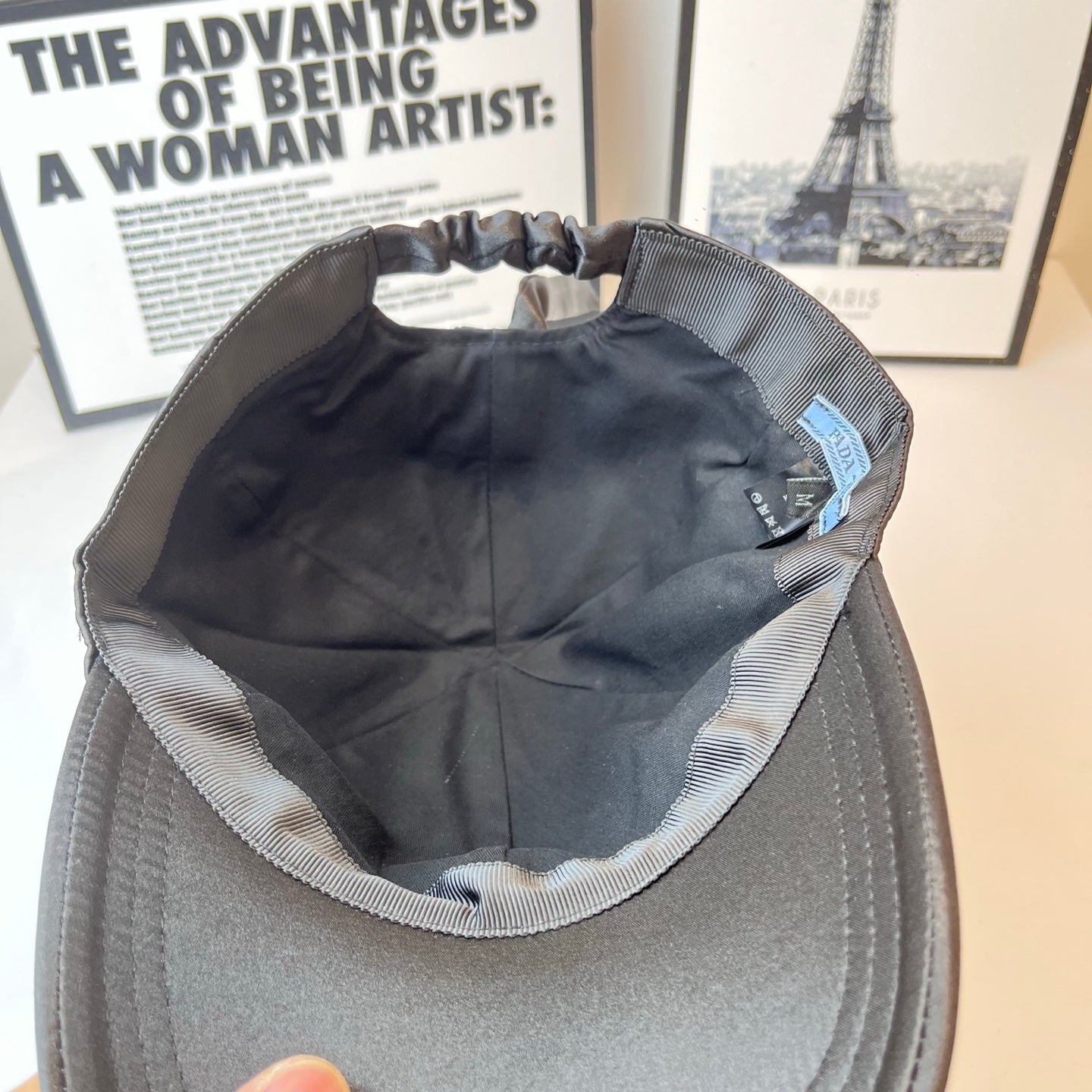 Prada cap interior with striped trim and blue brand label inside front.