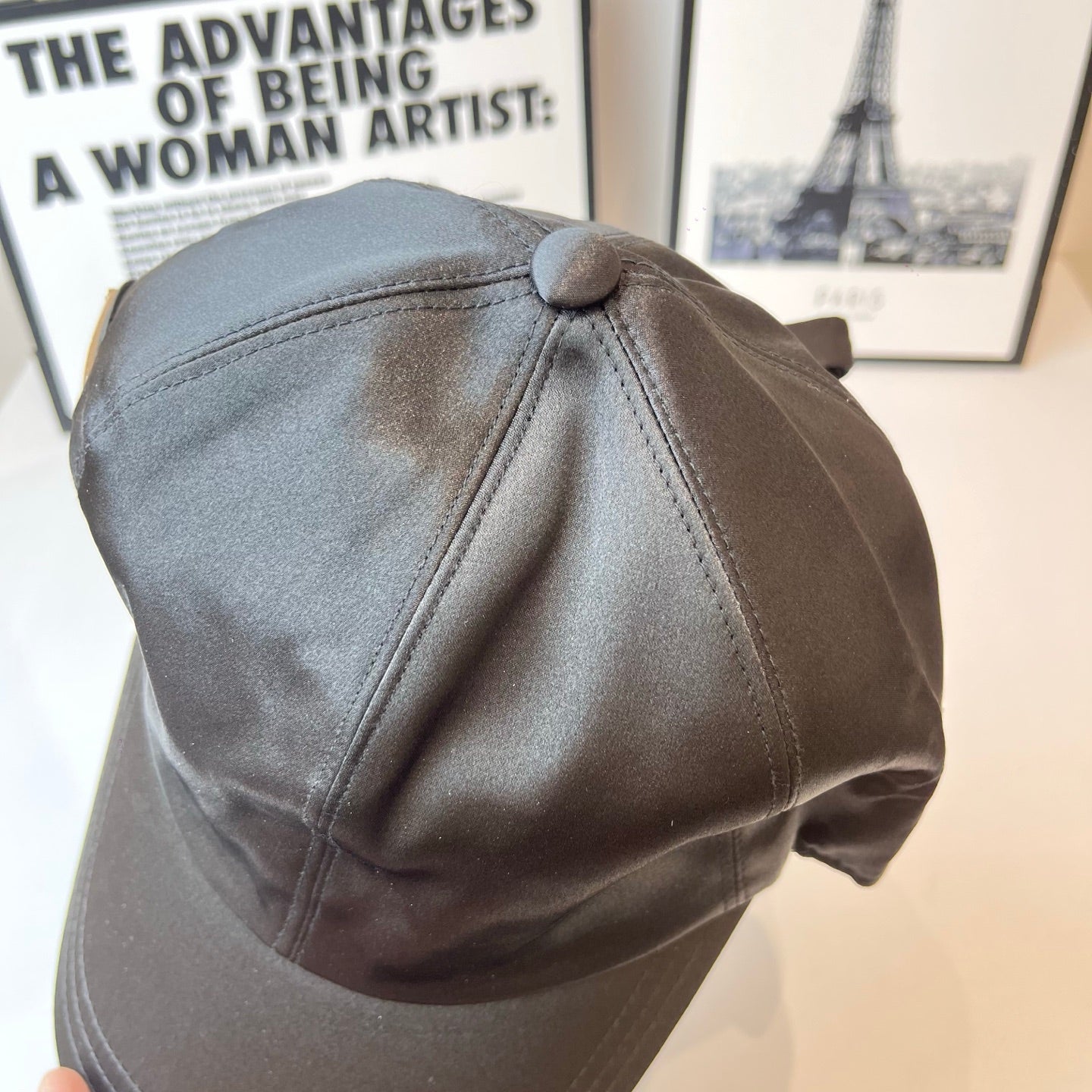 Prada cap side view with top button and curved panel stitching in gray.