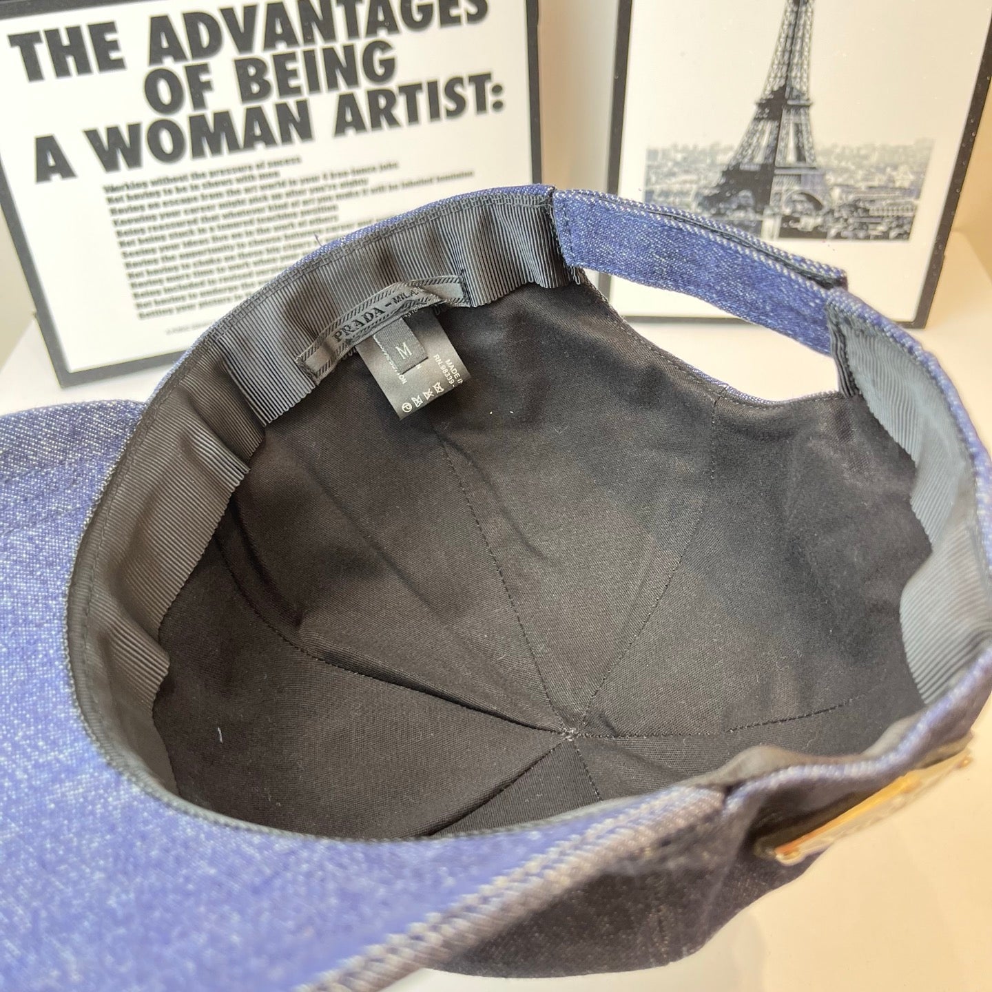 Prada denim cap interior with black lining and small fabric tag near crown.