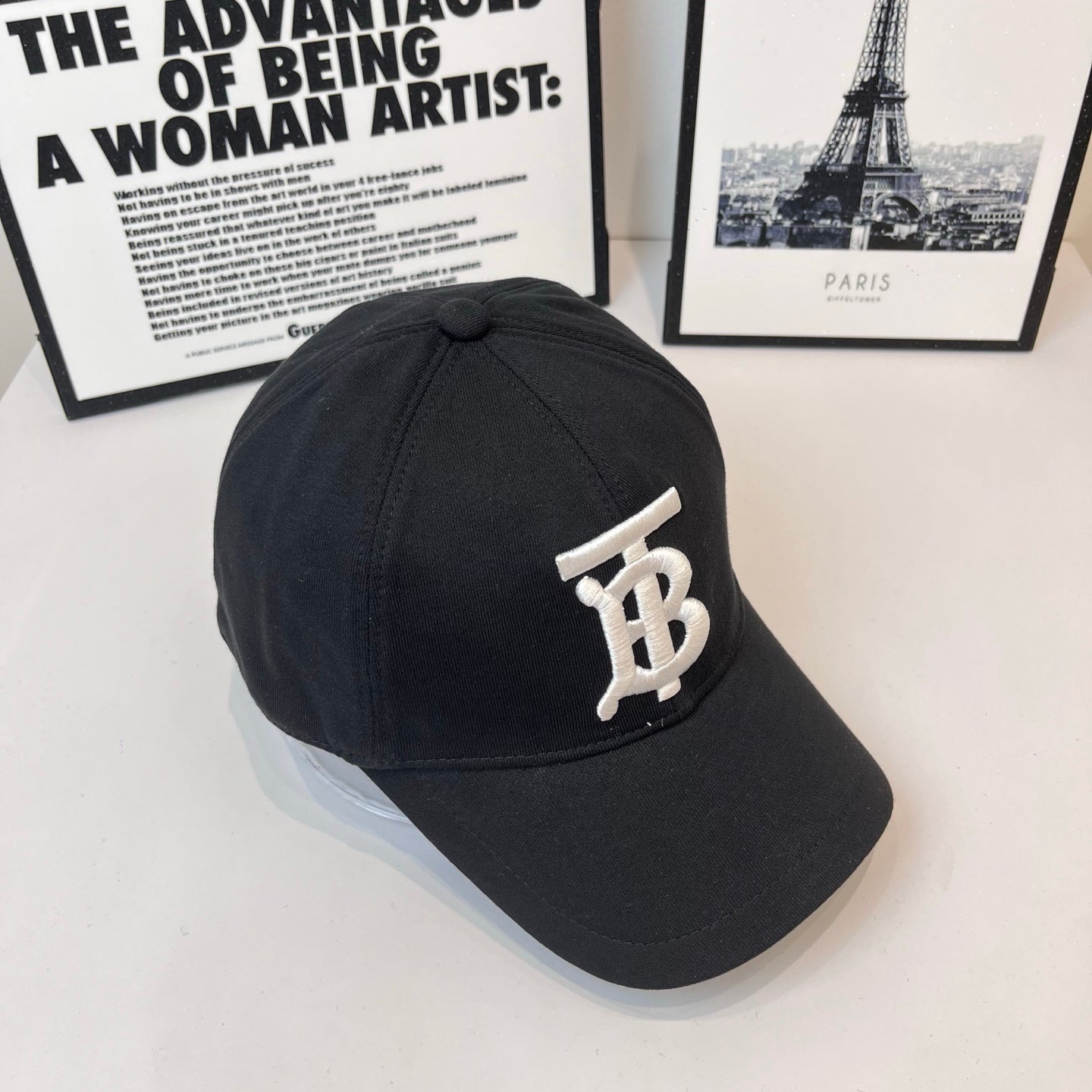 Black Burberry cap side view with white TB monogram badge