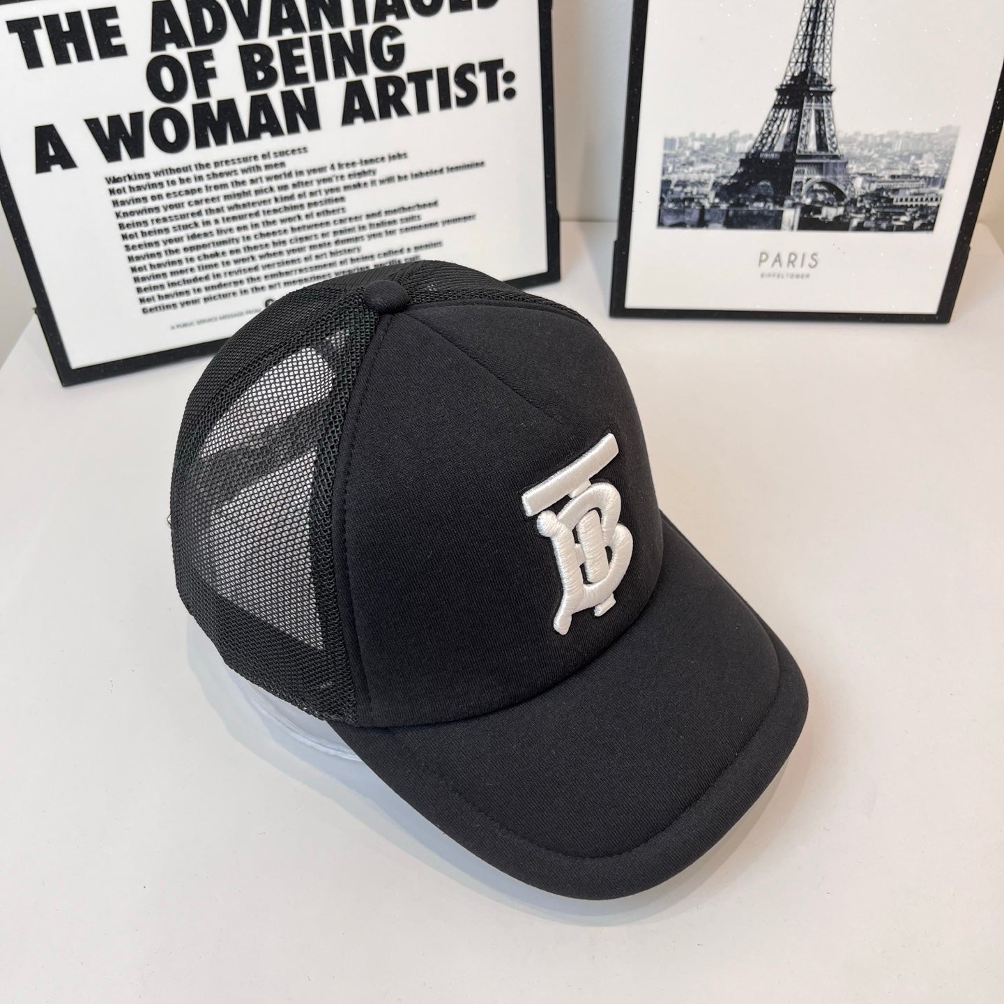 Black baseball cap with side mesh panels and white embroidered monogram logo