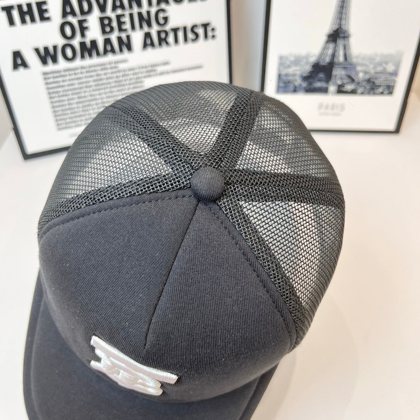Black mesh-back cap with stitched crown panels and small white logo detail