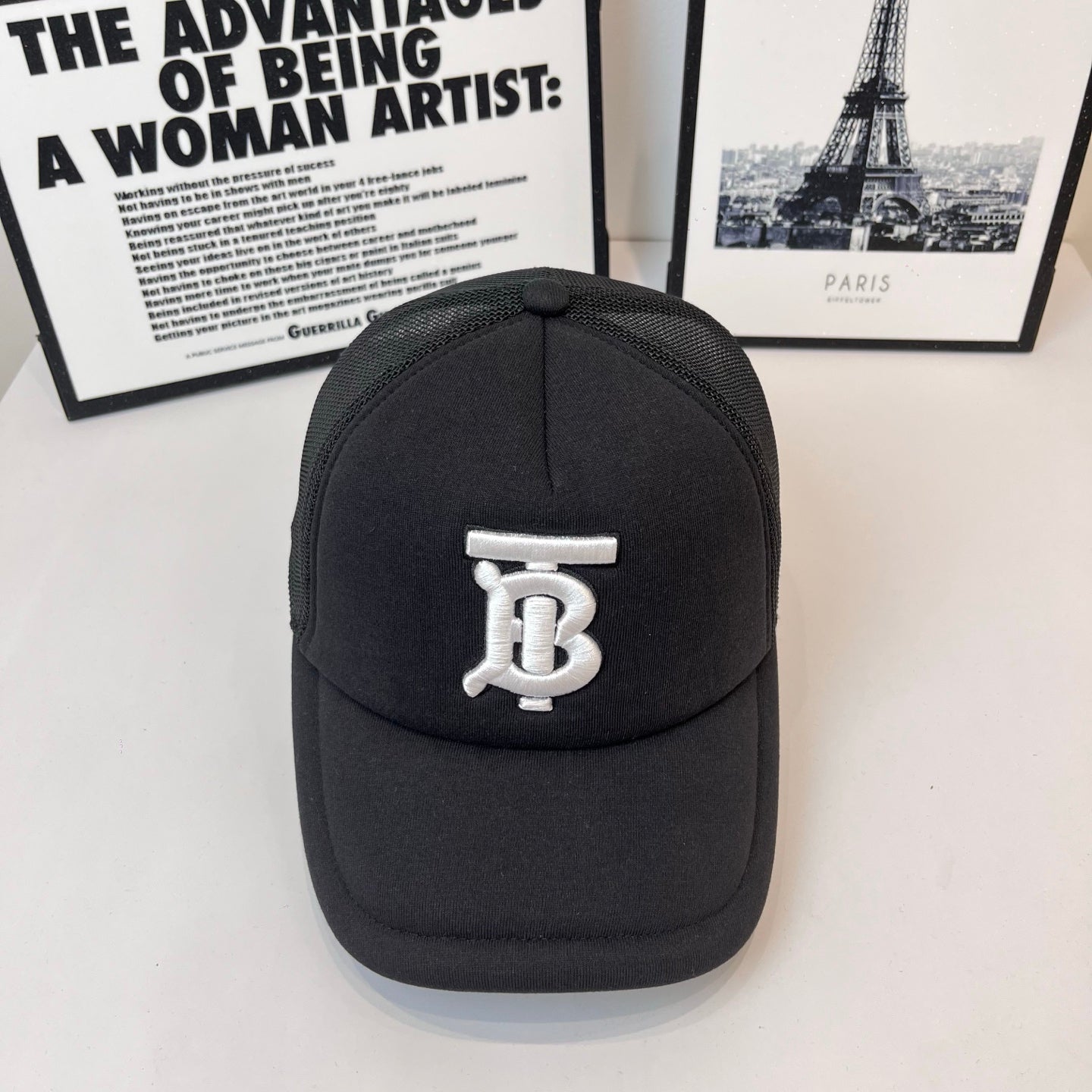 Black baseball cap with white embroidered monogram logo on front and curved brim