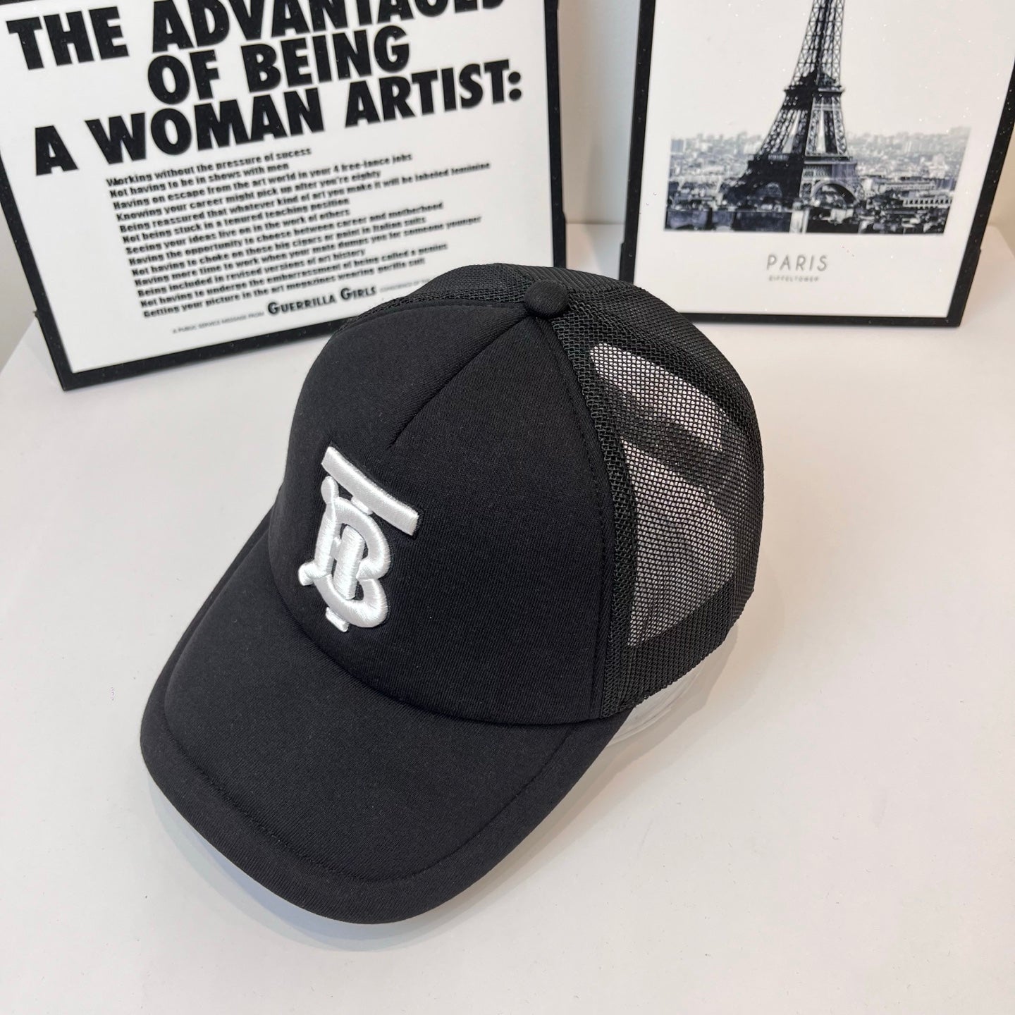 Black baseball cap with white embroidered monogram logo on side and mesh panel