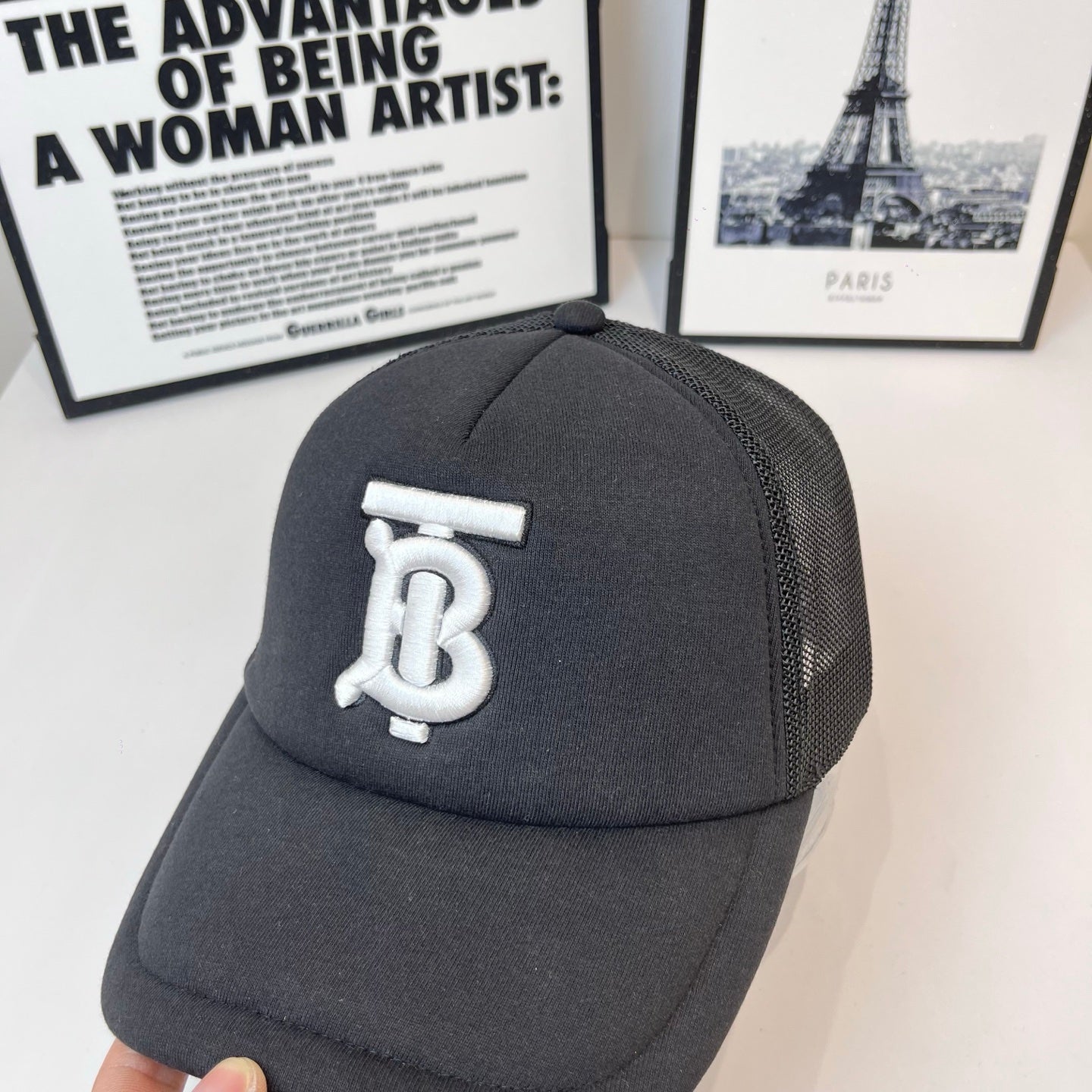 Black baseball cap with front white monogram logo and mesh side panel