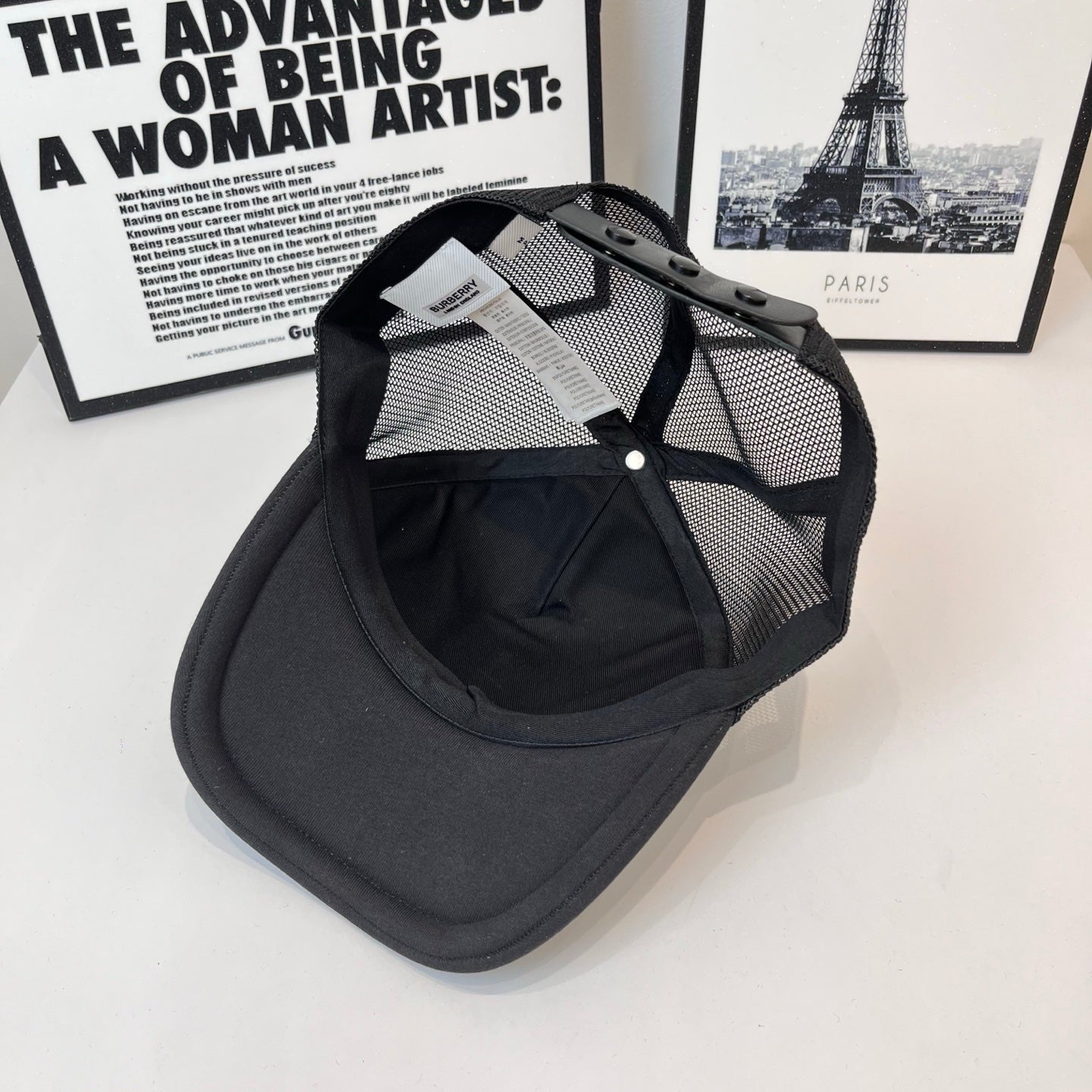 Black baseball cap with mesh side panels and adjustable strap detail near crown