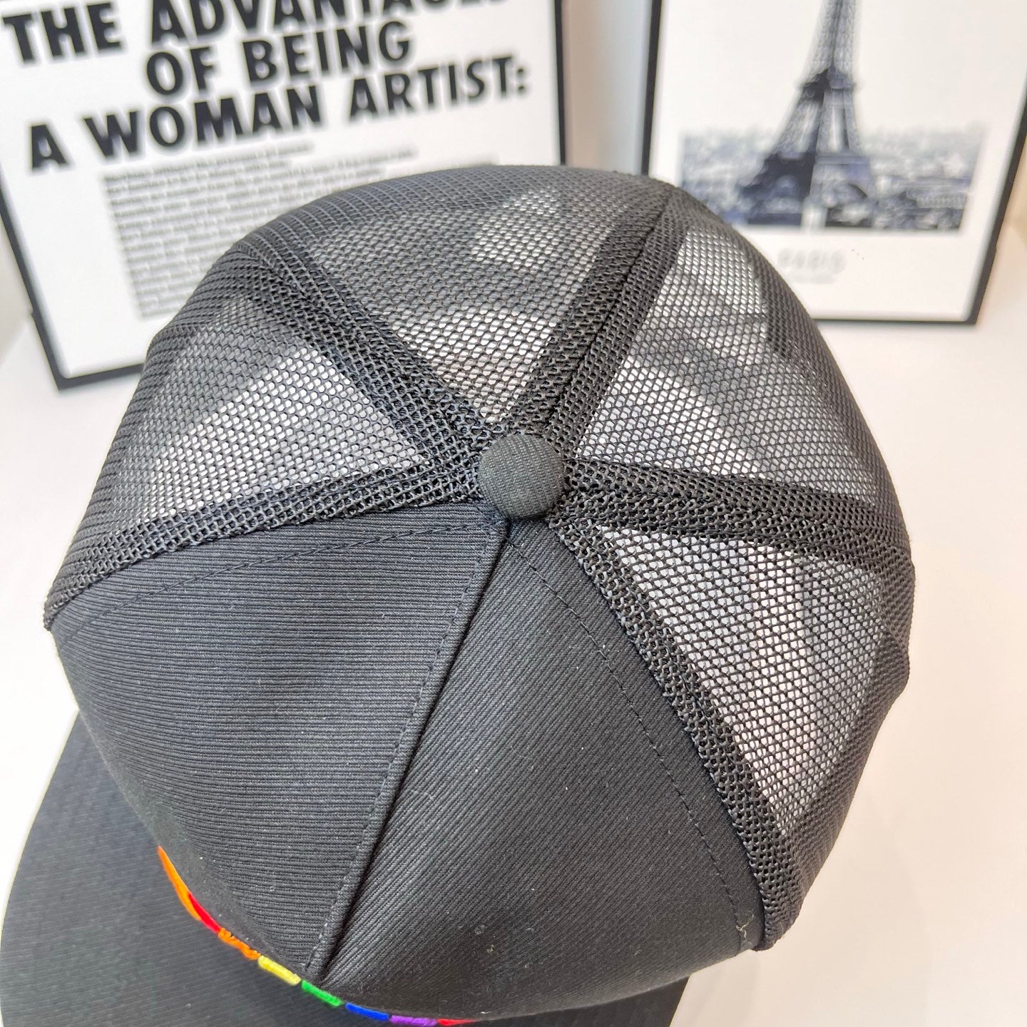 Black mesh baseball cap top view with rainbow-stitch brim edge