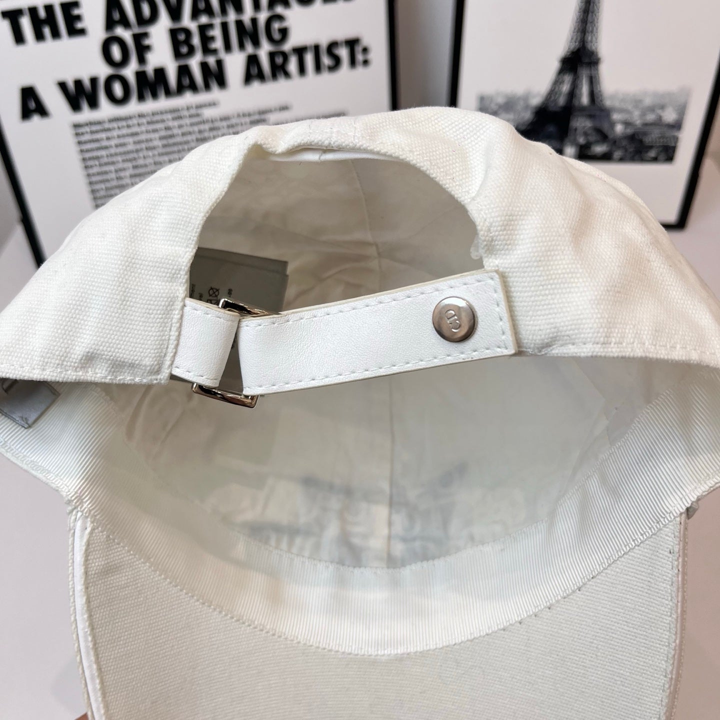 White canvas cap strap with metal buckle on back opening.