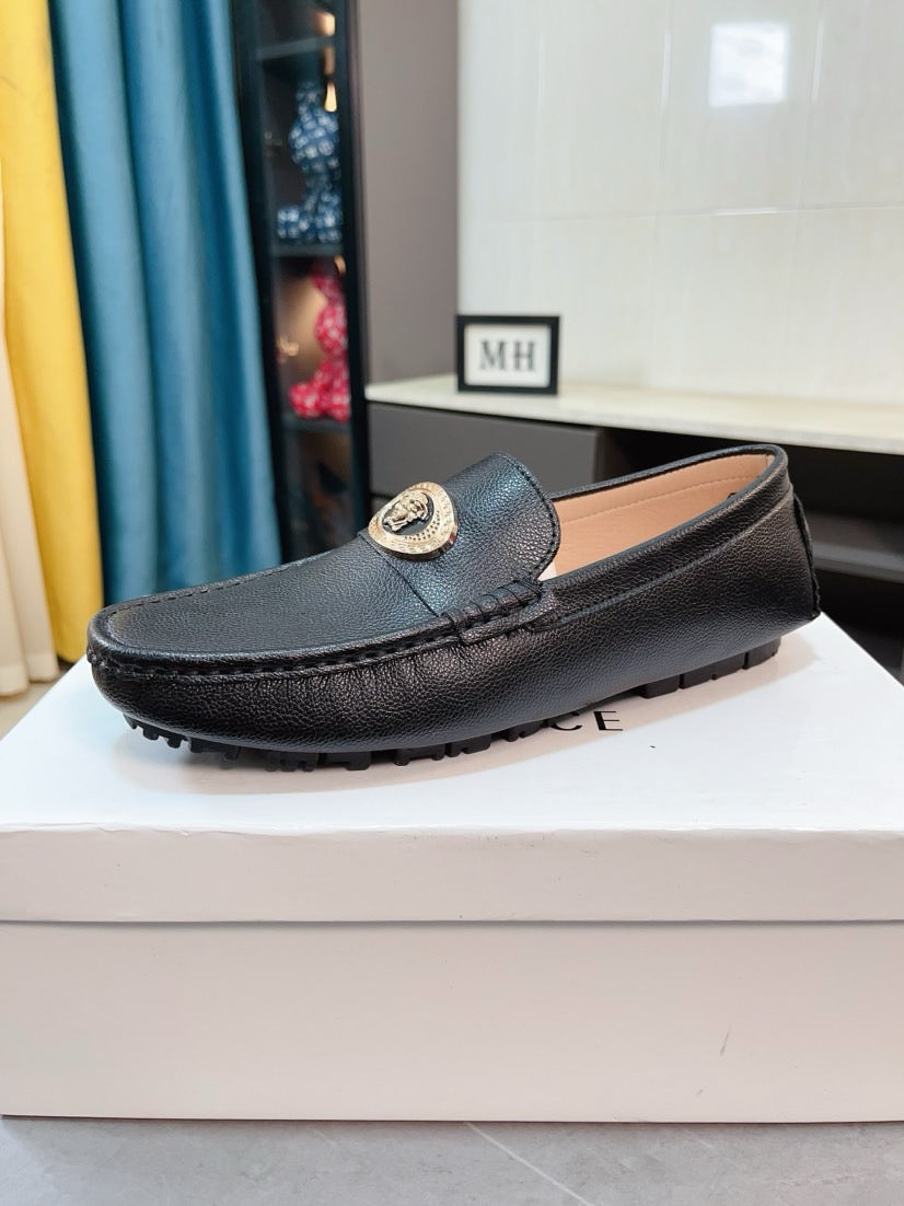 Black leather loafer with gold medallion ornament on front strap
