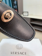 Black leather loafer toe with gold medallion emblem and stitched edge