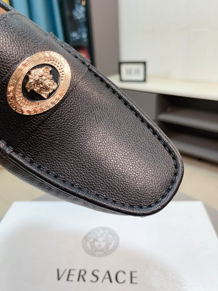 Black leather loafer toe with gold medallion emblem and stitched edge